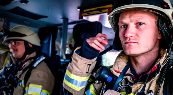 Zwei Feuerwehrmänner in voller Montur, bereit für den Einsatz. Die Serie "Feuer und Flamme Staffel 10" zeigt ihren Alltag.
