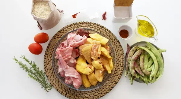 Ingredientes para hacer una paella: arroz, pollo, conejo, judías verdes, tomates, aceite de oliva, pimentón y azafrán.
