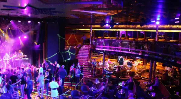 En livlig scen med ett band som spelar, folk som dansar och sitter vid bord. En trappa leder upp till en annan nivå. En typisk bild av stockholm nightlife.