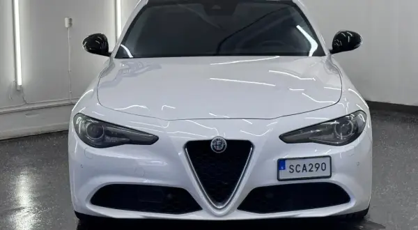 Vit Alfa Romeo Giulia, en elegant begagnad bil med mörk tak och svarta backspeglar. Perfekt för dig som söker stil och prestanda.