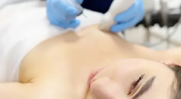 Lekarz wykonuje biopsję gruboigłową guzka, być może gruczolakowłókniaka, u pacjentki.