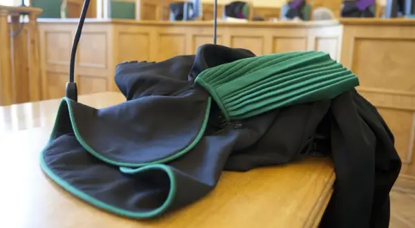 Toga adwokacka na stole w sali sądowej. Zastanawiasz się, ile zarabia adwokat z urzędu?