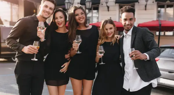 Fünf Freunde in eleganter Cocktailgarderobe stoßen mit Champagner an.