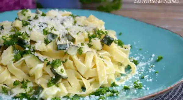 Assiette de tagliatelle de courgette crémeuse, parsemée de persil frais et de parmesan râpé. Un délice léger et savoureux.