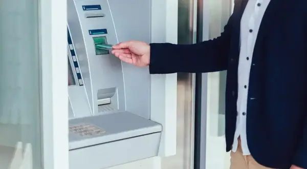 Mężczyzna w garniturze wkłada kartę do wpłatomatu euro. Szybka transakcja w bankomacie.