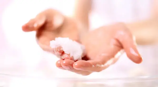 Zwei Hände halten eine kleine Menge eines selbstgemachten Peelings. Perfekt zum Handpeeling selber machen zum Verschenken.