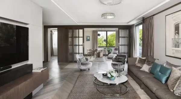 Elegancki salon z kanapą, fotelami i stolikiem kawowym. W tle widać jadalnię i okno z widokiem na zieleń. Całość emanuje wyrafinowanym, **włoskim stylem**.