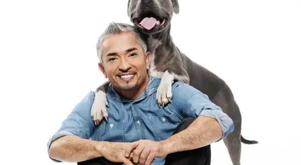 Cesar Millan, znany psi behawiorysta, z psem opartym o jego ramiona.