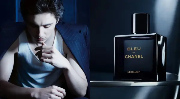 Młody mężczyzna w garniturze i podkoszulku, obok flakonik perfum BLEU DE CHANEL L'EXCLUSIF.