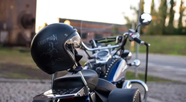 Czarny kask motocyklowy z napisem "Scorpion" i grafiką skorpiona, oparty o siedzenie choppera.