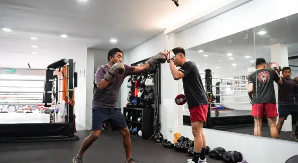 Two men train in a boxing gym, one throwing a punch while the other defends. This image captures the intense **boxing mindset** required for the sport.