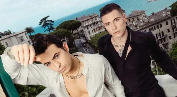 Benji e Fede posano con un panorama mozzafiato alle loro spalle, tra case colorate e il blu del mare.