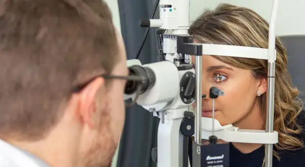 Un ophtalmologue examine l'œil d'une patiente avec un biomicroscope.