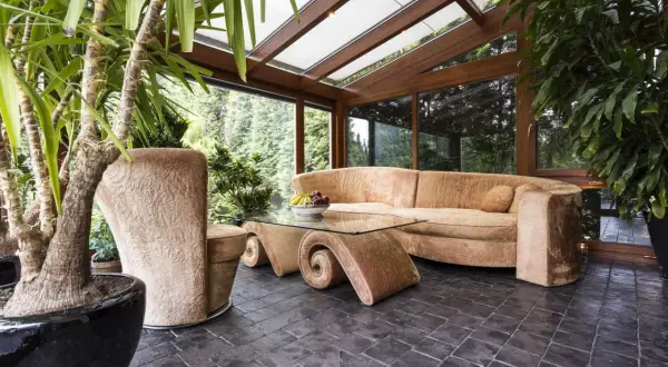 Gemütlicher Wintergarten mit üppiger Bepflanzung, bequemer Couch und einem einzigartigen Couchtisch. Tolle Ideen für Ihren Wintergarten!