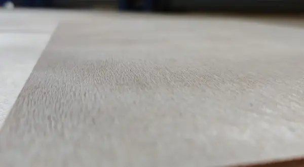 Textura de madera de okume arbol, con vetas finas y claras, mostrando la belleza natural del material.