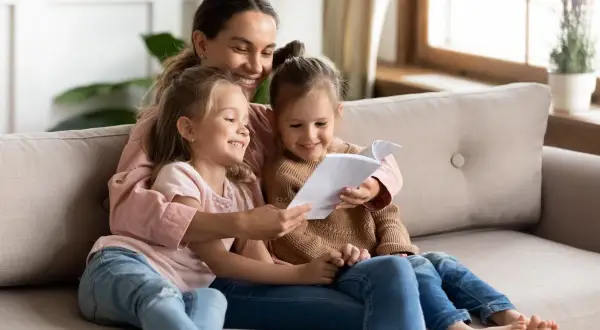 Mama czyta swoim córeczkom krótkie wierszyki dla bff. Radość i bliskość na kanapie.