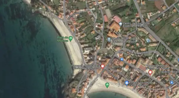 Vista aérea de la **playa de Madorra**, con el mar turquesa y la arena dorada. Se aprecian edificios y calles cercanas.