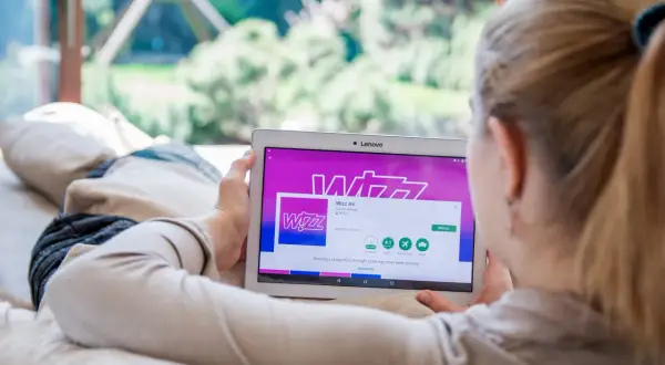 Kobieta przegląda w aplikacji Wizz Air na tablecie, planując tani lot.