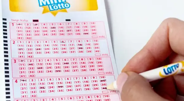 Dłoń z ołówkiem zaznacza liczby na kuponie Mini Lotto. Sprawdzanie lotto centrum wyniki to emocjonujący moment.