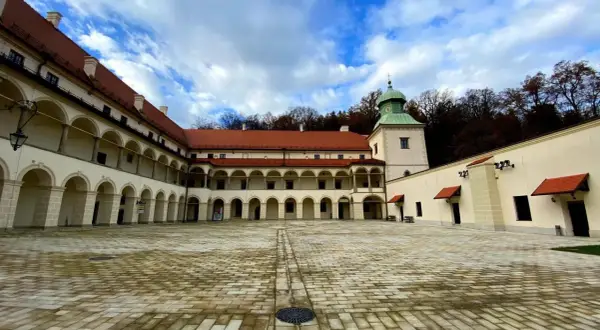 Dziedziniec zamku Sucha Beskidzka z arkadowymi krużgankami i wieżą.