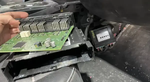 Ręka trzyma moduł elektroniczny z zieloną płytką drukowaną, prawdopodobnie związany z błędem dtc u0140 opel. Obok widoczny inny moduł.