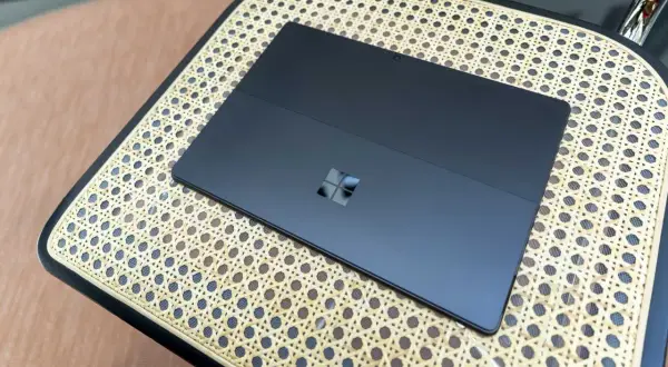 Ciemny tablet z logo Windows na plecach, działający na Windows 11 ARM, leży na plecionej powierzchni.