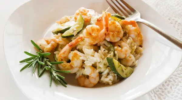 Cremiges Risotto mit Garnelen und Zucchini, garniert mit Rosmarin. Ein köstliches Gericht, das Lust auf mehr macht.