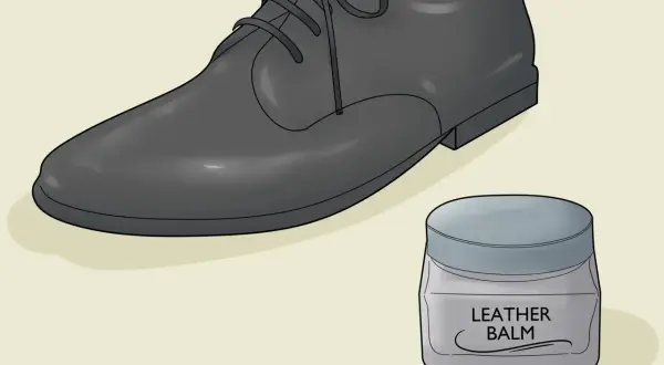 Un soulier en cuir noir et un pot de baume pour cuir. Apprenez comment assouplir des chaussures en cuir pour un confort optimal.