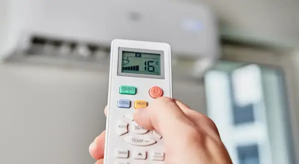 Main tenant effectue le réglage clim télécommande pour une température de 16°C.