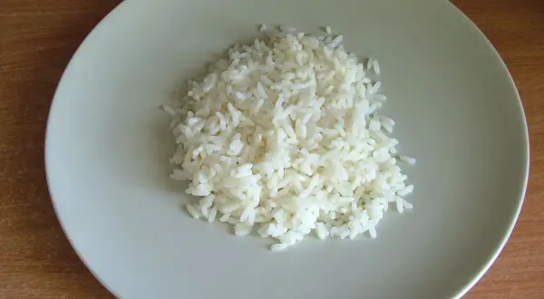 Ugotowany ryż na jasnoszarym talerzu.
