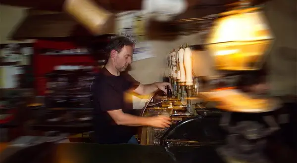 Barista serve birra a un beer fest, con spillatori e bicchieri in movimento.
