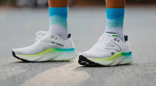 Białe buty do biegania New Balance z kolorową podeszwą i skarpetki w chmurki. Dowiedz się, jak dobrać buty do biegania.