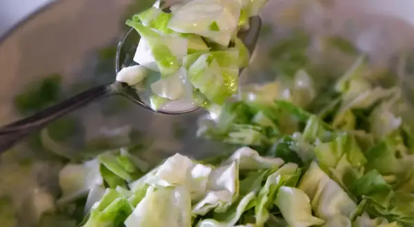 Łyżka z posiekaną kapustą ze śmietaną, gotową do podania.
