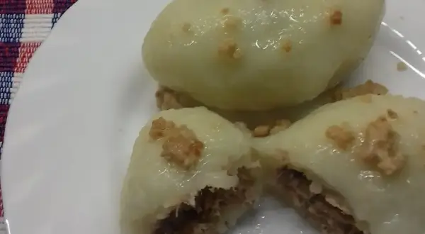 Pyszne pyzy z mięsem, gotowe do jedzenia. Jedna pyza jest przekrojona, ukazując soczyste nadzienie.