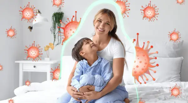 Matka tuli dziecko, które ma kaszel w nocy. Wokół nich unoszą się wirusy, ale chroni je zielona bariera.