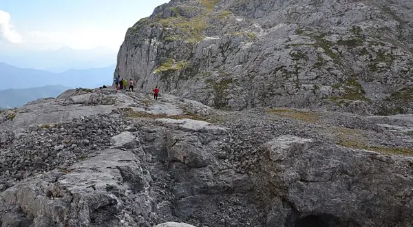Senderismo en la vega de Liordes, un paisaje rocoso con un grupo de personas observando un abismo.