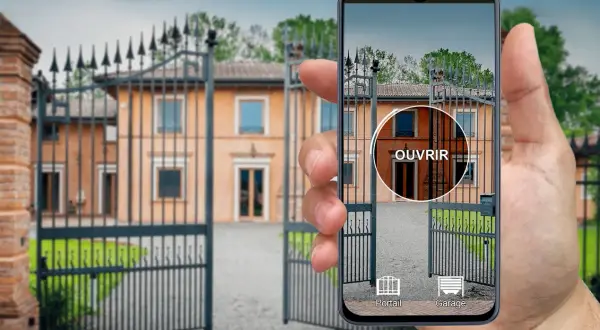 Une main tient un iPhone affichant une application de télécommande universelle pour ouvrir le portail d'une villa.