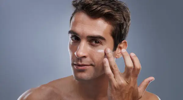 Hombre aplicándose crema en el rostro. El cuidado facial del hombre es esencial para una piel sana y radiante.