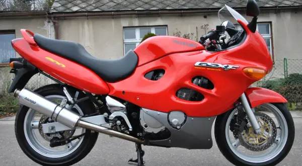 Czerwony motocykl Suzuki GSX-F 600 z czarnym siedzeniem, zaparkowany przed budynkiem.