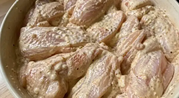 Rå kycklingbitar i en krämig marinad. Denna yoghurtmarinerade kyckling ser ut att bli otroligt saftig och smakrik.