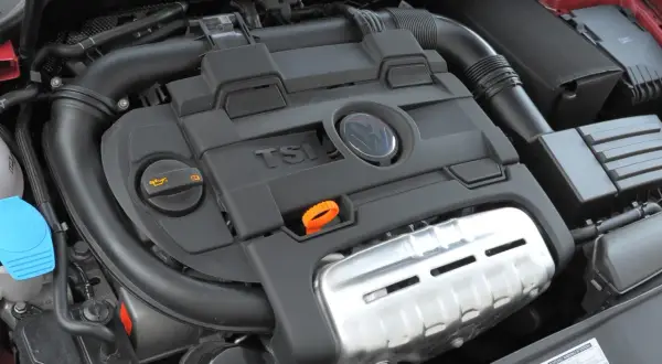 Silnik 1.4 TSI z widocznym logo VW. Widoczne elementy układu dolotowego i osłony silnika.