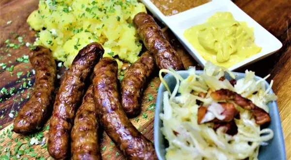 Herzhafte Rehbratwurst mit Kartoffelpüree, Krautsalat und Senf. Ein tolles rehbratwurst rezept für Genießer.