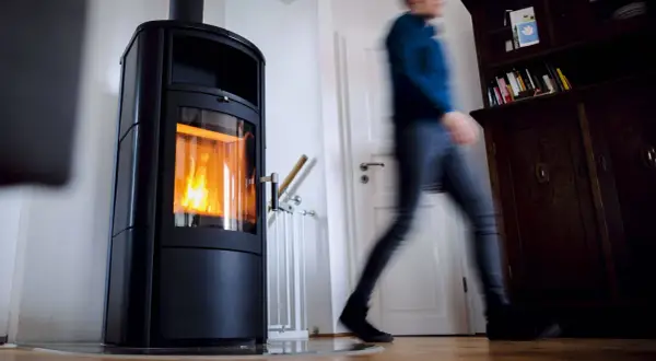 Ein Mann eilt an einer brennenden Holzheizung vorbei. Angesichts des möglichen Holzheizung Verbots 2030, wird diese Heizform bald Geschichte sein.