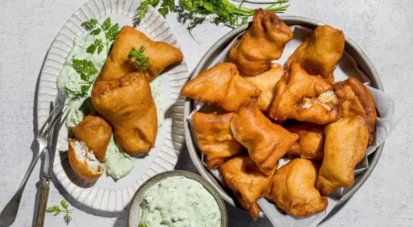 Fritti dorati di lucioperca, perfetti per le tue ricette. Serviti con salsa verde e guarniti con prezzemolo fresco.