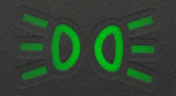 Zielony symbol świateł mijania na ciemnym tle.