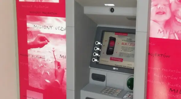 Bankomat Millennium z hasłem "miliony uśmiechów". Obok reklamy z uśmiechniętymi dziećmi i hasłem "miliony uczuć".