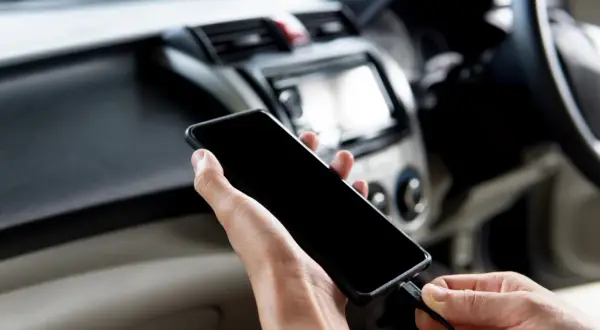 Ręce podłączają telefon do radia samochodowego, aby dołożenie bluetooth do radia samochodowego było proste.