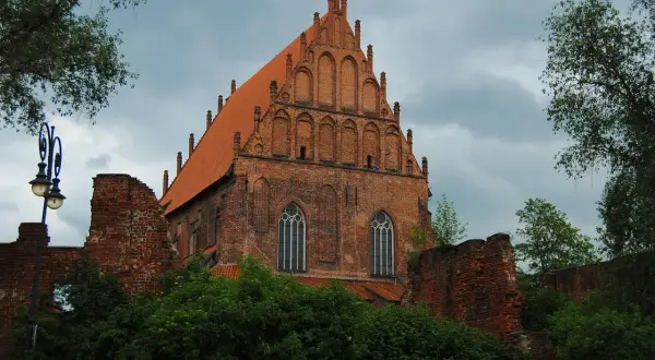 Gotycka ceglana bazylika w **starym mieście Elbląg** z charakterystycznym szczytem i dachówką.