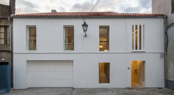 Fachada moderna con pintura al pliolite, puerta de garaje, ventanas y entrada iluminada.