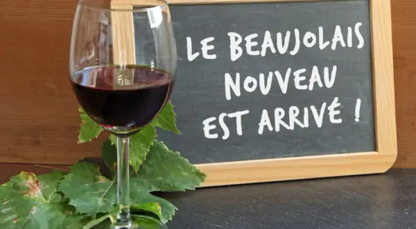 Kieliszek czerwonego wina i tablica z napisem "Le Beaujolais Nouveau est arrivé!" – to znak, że nadszedł czas na święto młodego wina.